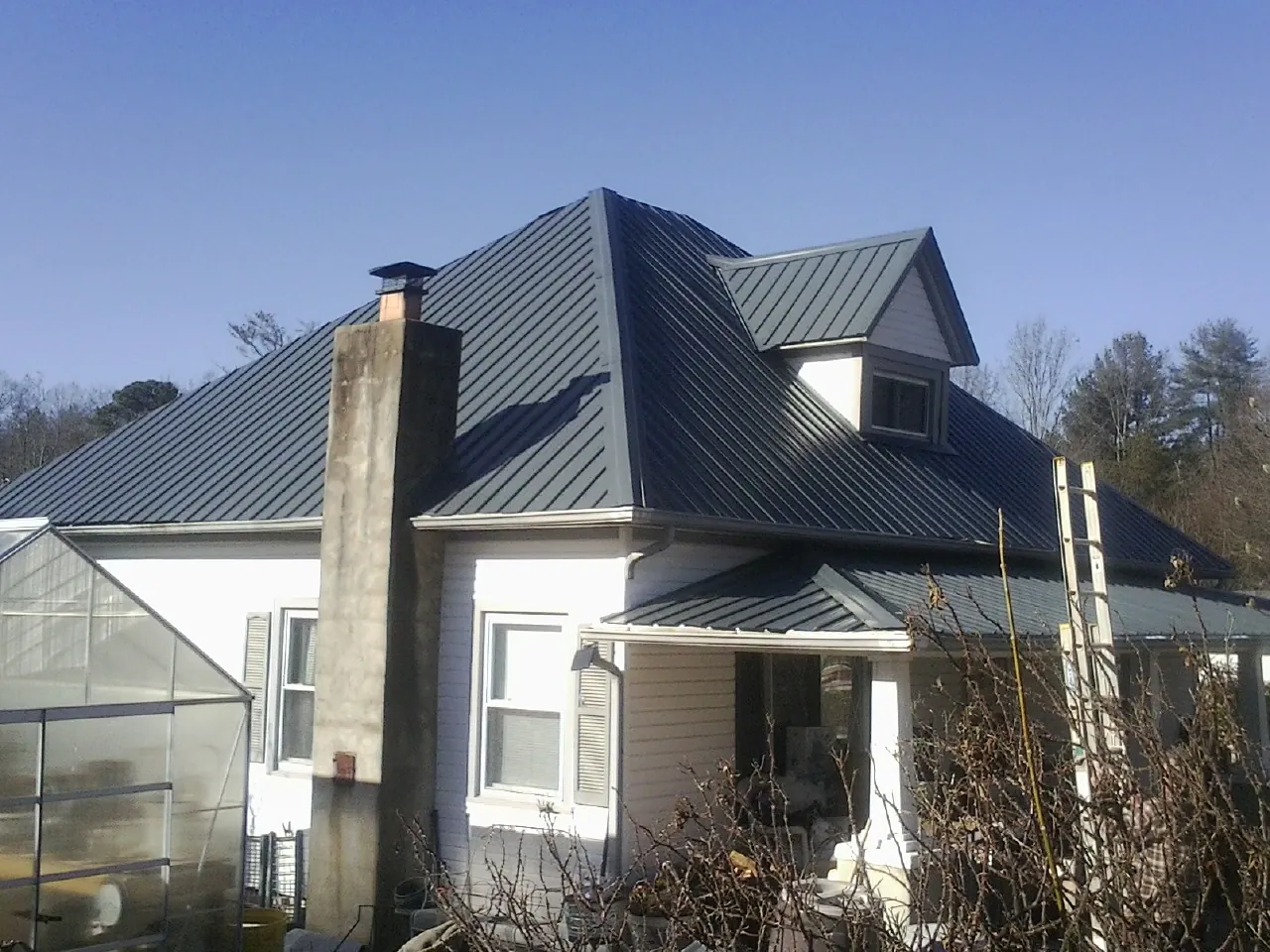 Dark blue standing seam metal roof on a white farmhouse with dormer — Slate & Tile Roof Repair by Roofing Brothers in Cotati