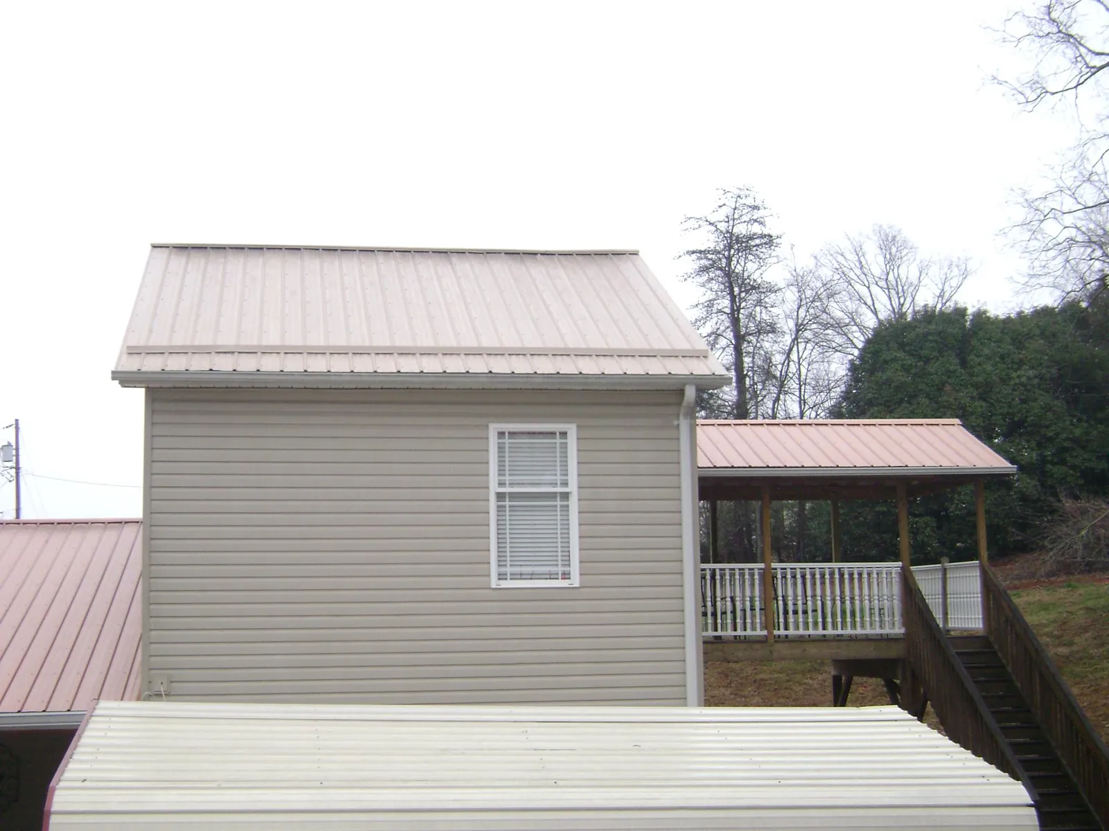 Tan metal roofs on a two story addition and attached porch, from a Roof Replacement job in Cotati