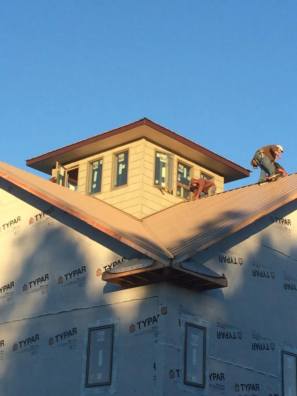 Roofers working around a rooftop cupola on a new metal roof at sunset — Roof Waterproofing in Cotati by Roofing Brothers